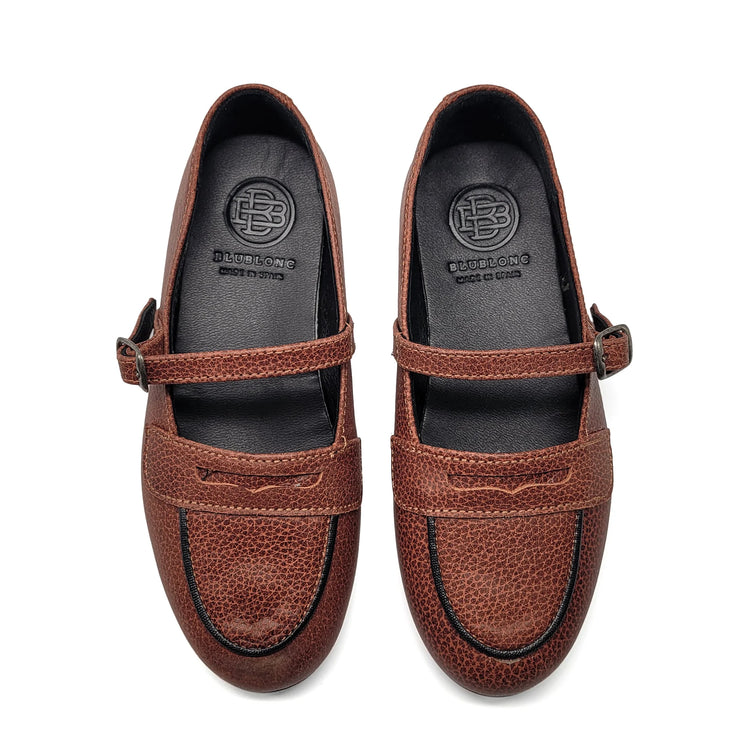 Pair of brown loafers with a strap on a white background
