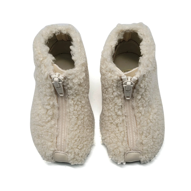Pair of beige fleece slippers with zippers on a white background