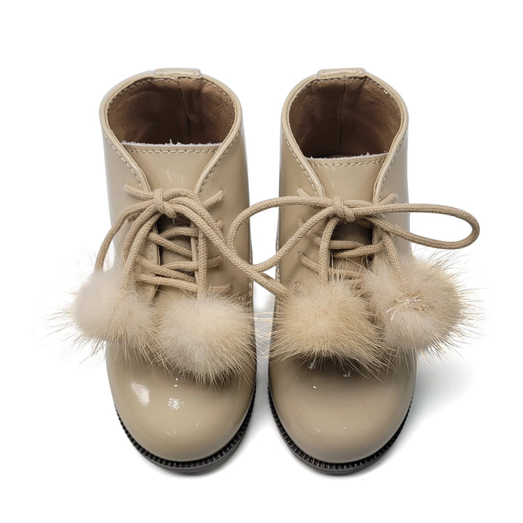 Beige children's boots with fur pom-poms on a white background