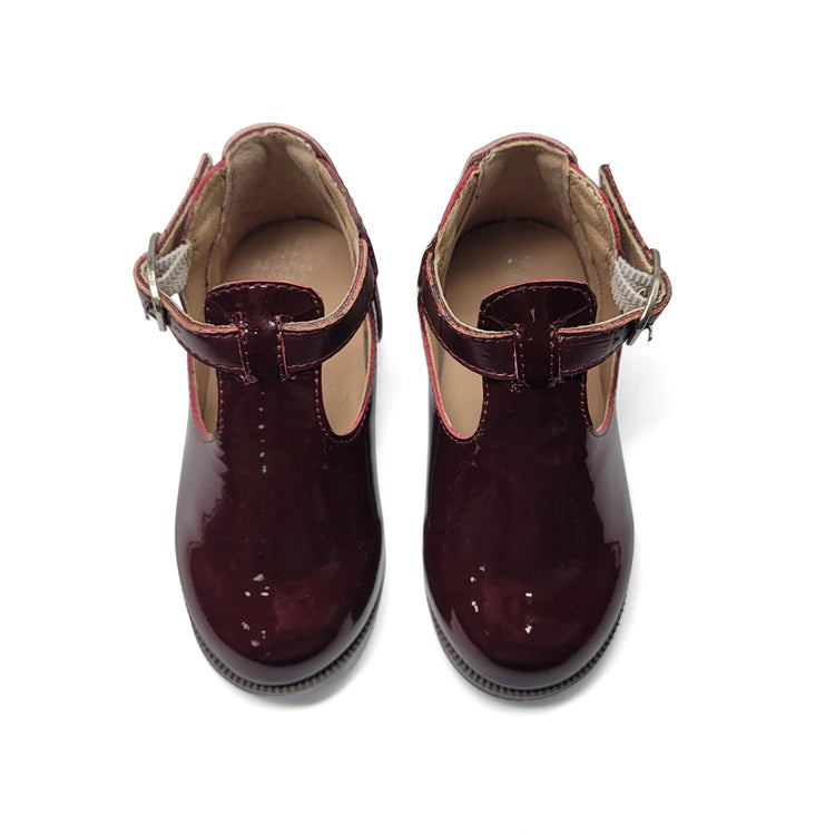 Pair of maroon children's shoes with a strap on a white background