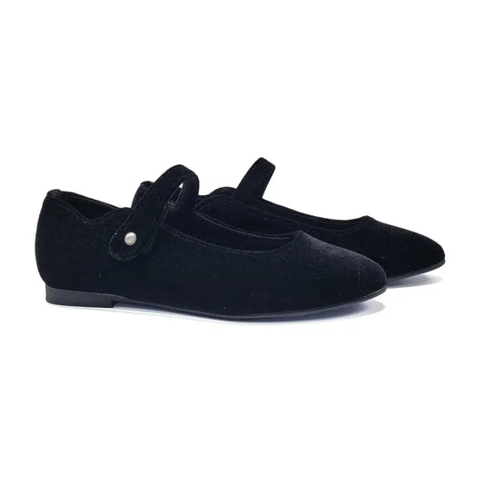 Pair of black velvet shoes with a strap on a white background