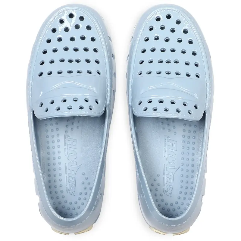 Pair of light blue slip-on shoes with a brand logo on a white background