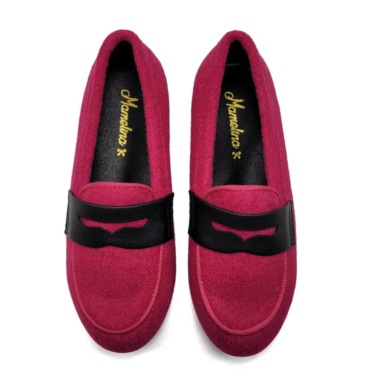 Pair of pink loafers with black straps on a white background