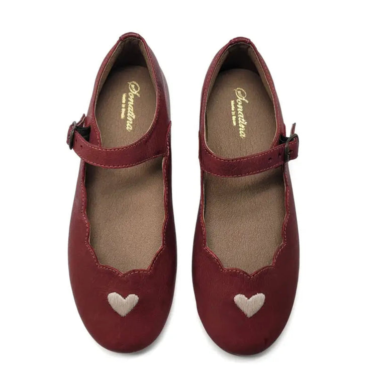 Pair of red shoes with heart designs on a white background