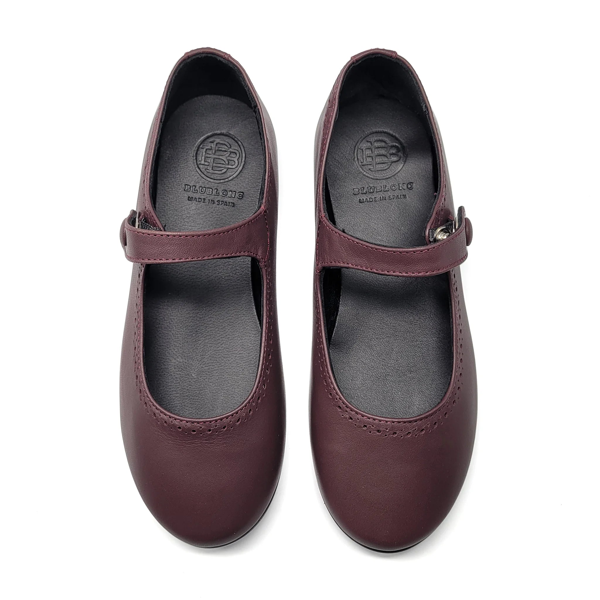 Pair of maroon shoes with a snap on a white background