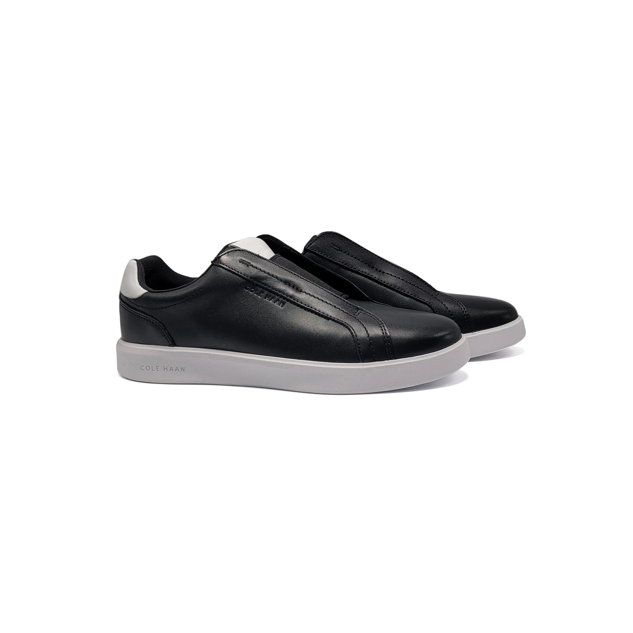 Black slip-on sneakers with white soles on a white background