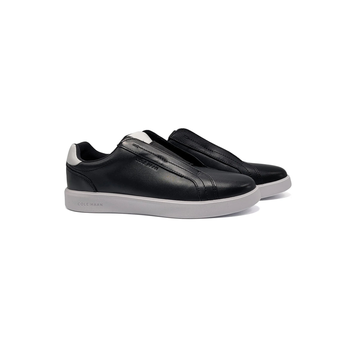 Black slip-on sneakers with white soles on a white background