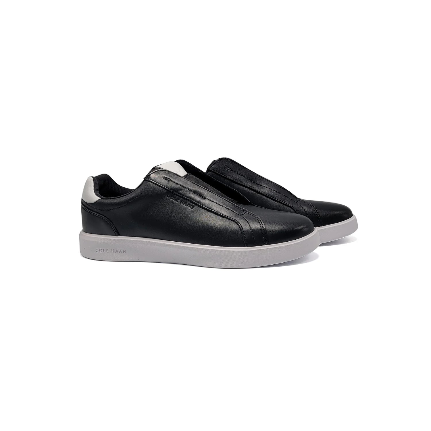Black slip-on sneakers with white soles on a white background