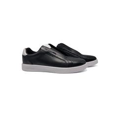 Black slip-on sneakers with white soles on a white background