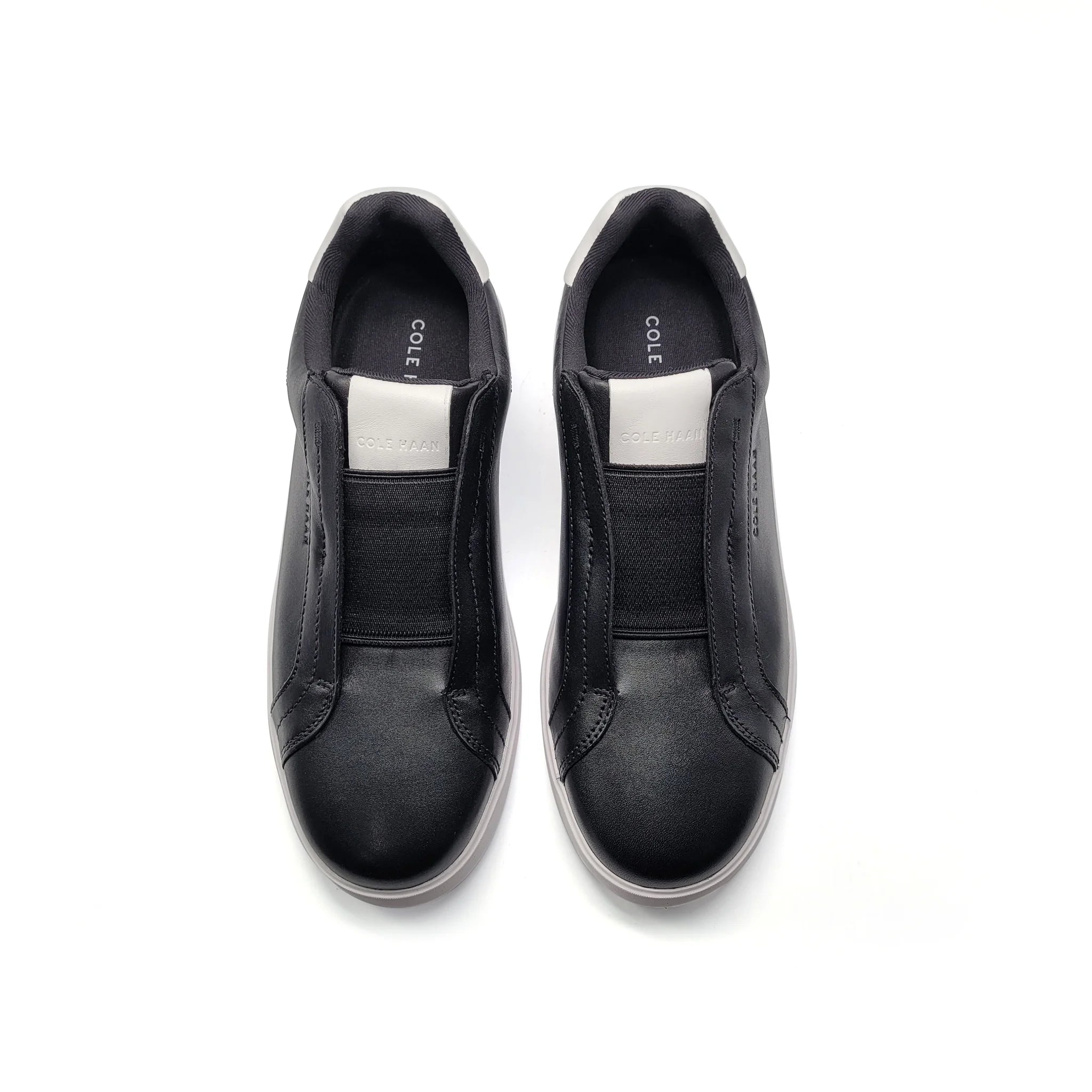 Black slip-on shoes with 'Cole' branding on a white background
