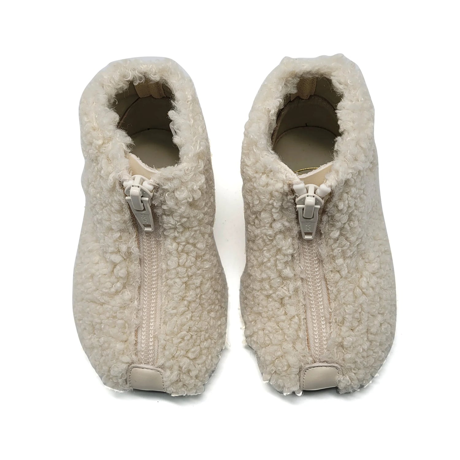Pair of beige fleece slippers with zippers on a white background