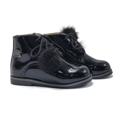 Black patent leather boots with fur pom-poms on a white background