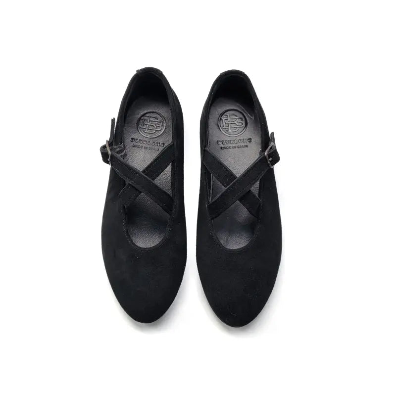 Pair of black mary jane with a criss-cross strap on a white background