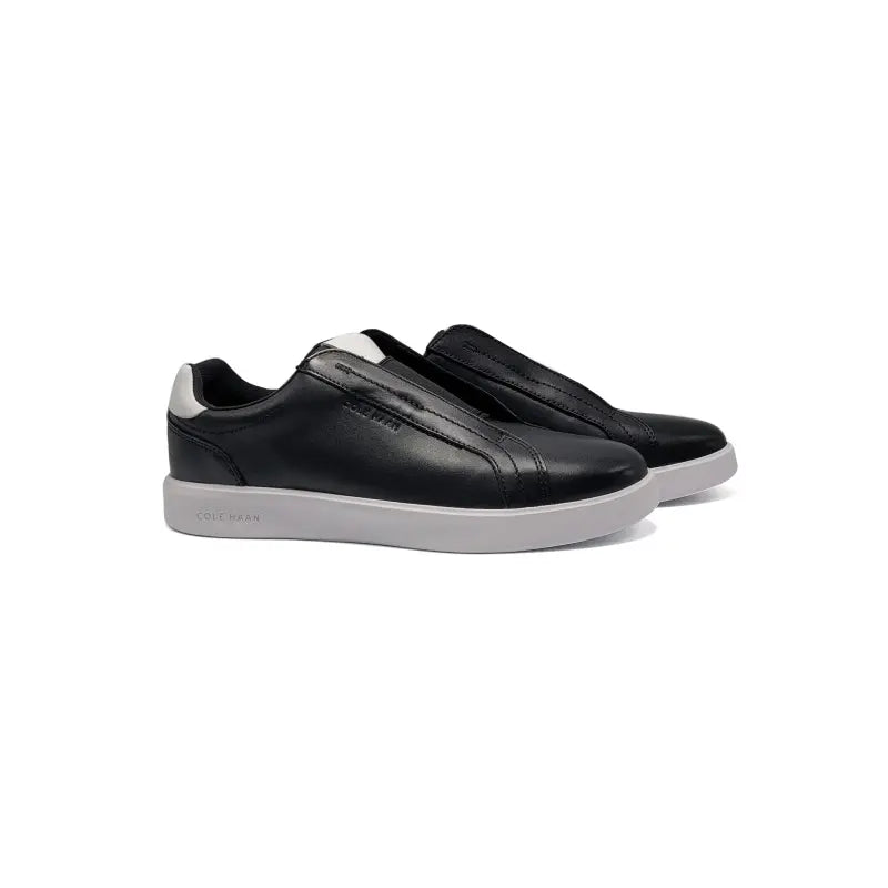 Black slip-on sneakers with white soles on a white background