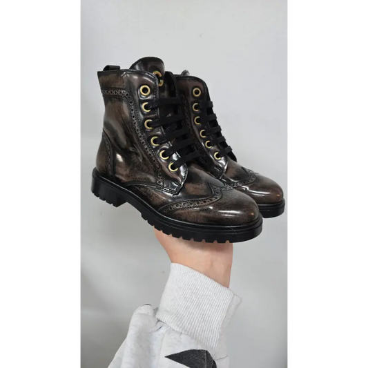 Brown leather boots being held against a light gray background
