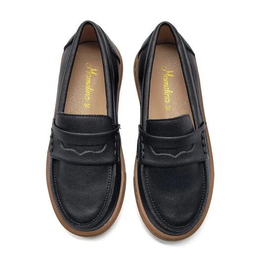 Black loafers with brown soles on a white background