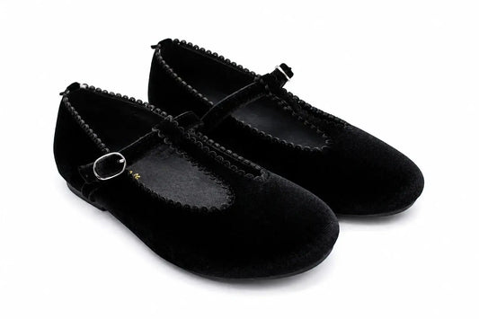 A pair of black velvet Mary Jane flats with braided trim and small silver buckle details, shown on a white background.