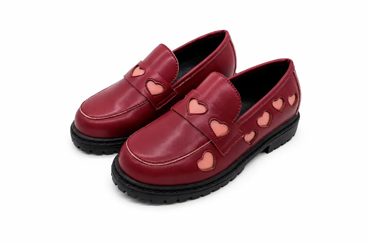 A pair of red leather slip-on loafers with heart-shaped cutouts on the strap and along the side, featuring black soles, shown on a white background.