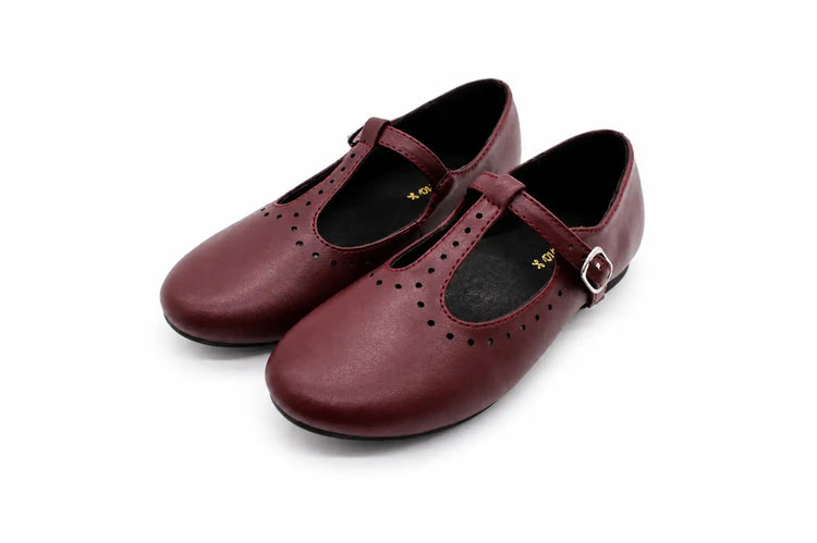 A pair of burgundy leather T-strap Mary Jane shoes with decorative perforations and a small silver buckle, shown on a white background.