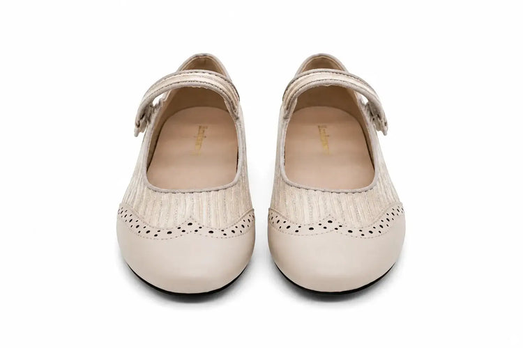 A pair of beige Mary Jane shoes with textured woven straps, decorative perforated detailing along the toe, and adjustable hook-and-loop straps, shown against a plain white background.