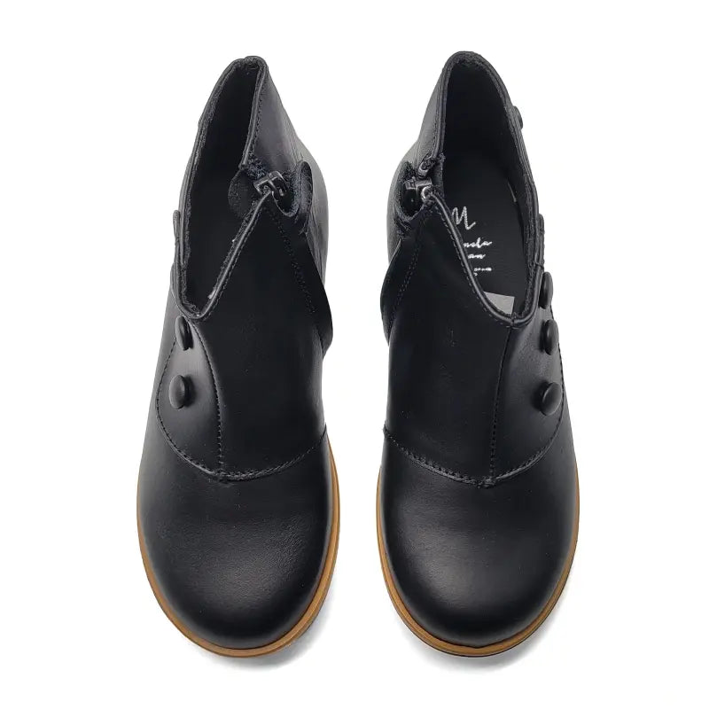 Pair of black leather shoes with brown soles on a white background