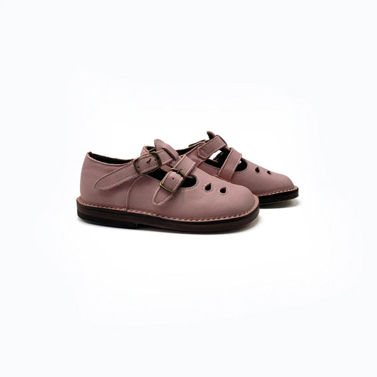 Pair of pink vintage shoes with brown soles on a white background